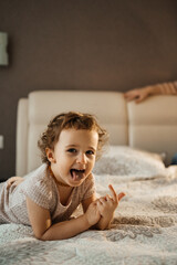 small girl lying on the sofa grimacing and showing her tongue