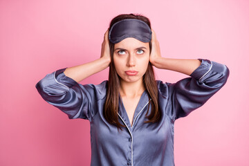 Photo portrait of tired girl covering ears with two hands isolated on pastel pink colored background