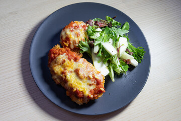 Chicken parmigiana with salad on the side.