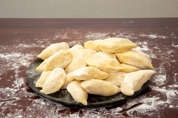 Pieroguis ,pierogis, perohê, verenek, Ukrainian food, in focus on the plate on the wooden table with wheat flour. Prudentópolis, Paraná, Curitiba Selective focus.