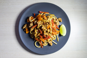 A plate of fried noodle with mince meat and vegetables.