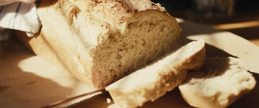 Knife cuts fresh hot baked bread cooking at home kitchen close up