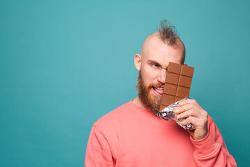 Bearded european man in casual peach isolated on turquoise background funny holding chocolate
