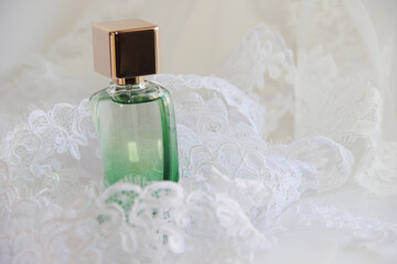 perfume or eau de toilette in a green bottle with a gold cap on a white background with delicate lace