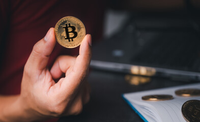Businessman's hand holding a gold Bitcoin on a laptop. Make money with bitcoin, blockchain transfer