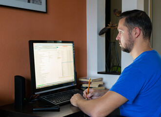 Fototapeta na wymiar Young man works on the computer online at home. Designer freelance work.