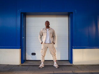 Handsome black Spanish male with hands in pockets posing at camera