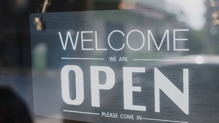 Welcome we're open vintage black and white retro sign on a coffee glass door cafe after coronavirus lockdown quarantine. Owner small business, food and drink, business reopen again concept.