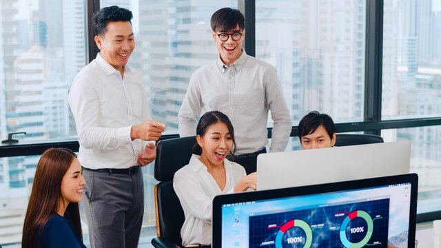 Millennial group of young businesspeople Asia businessman and businesswoman celebrate giving five after dealing feeling happy and signing contract or agreement at meeting room in small modern office.
