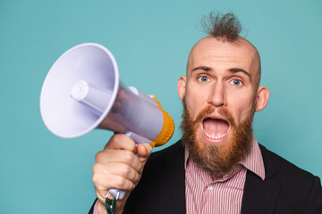 Bearded european businessman in dark suit isolated on turquoise background with megaphone shouting...