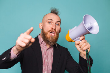 Bearded european businessman in dark suit isolated on turquoise background with megaphone shouting...