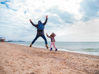 Father and daughter jumping flying in the air on empty beach. Lifestyle photo real people. Scenic marine landscape Vivid blue sea water sky. Happy active family having fun on vacation travel wallpaper