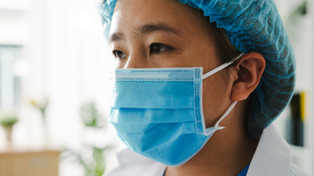 Young Asia lady doctor or nurse worker in latex protective gloves surgeon preparing for surgical operation and tired open eyes at health hospital office. Social distancing, quarantine for coronavirus.
