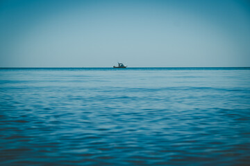 Small fishing boat on the horizon - minimalist seascape with copy space