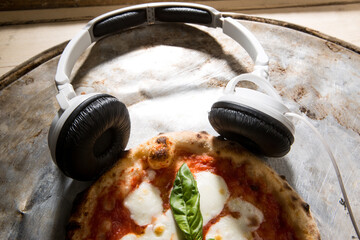 cuffie moderne bianche poggiate sopra una pizza margherita in un tavolo 
