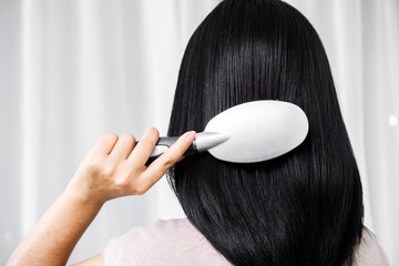 Asian woman hand holding comb brushing her beautiful long black and shiny hair - obrazy, fototapety, plakaty