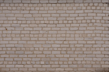 White brick wall. It is laid unevenly. A little darkened with age.
