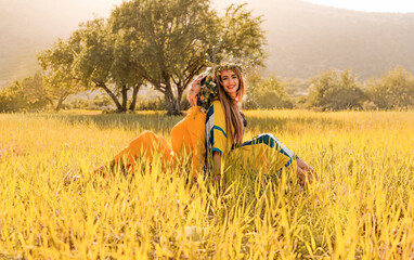Two women with wreaths on their heads in a field.