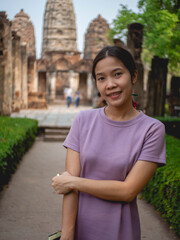 Fototapeta premium Woman wearing purple dress and old temple at Sukhothai, Thailand in March 13 2021