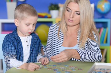 Woman and little boy playing with puzzles