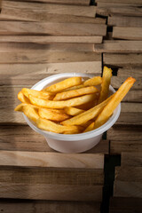 patatine fritte dentro un contenitore di plastica su un tavolo di legno