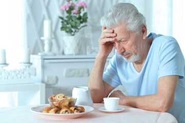 Elderly man drinking cup of coffee at home
