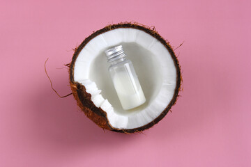 Bottle with coconut milk in a coconut on a pink background. Advertising design, menu, packaging. 