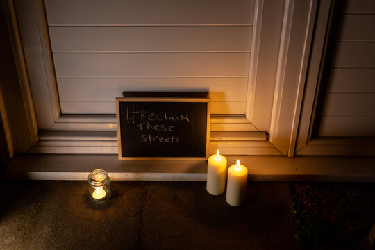A chalkboard with reclaim the streets on the doorstep of a house with a small tea light and 2 pillar candles to show solidarity