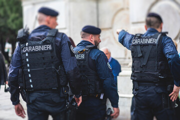 Italian Carabinieri, national gendarmerie of Italy squad,  of Italy patrol formation back view with "Carabiners" logo emblem on uniform maintain public order in the streets of Florence, Tuscany, Italy