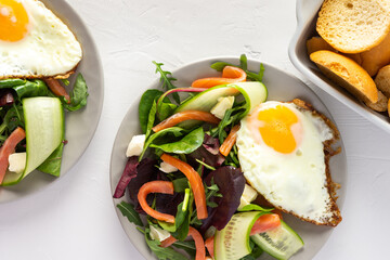 Fresh organic mesclun mix salad with cucumber, mozzarella and salmon, scrambled eggs and dry buns , delicious hearty breakfast