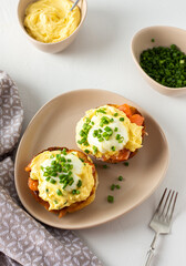 Delicious hearty breakfast, eggs Atlantic in a plate on a white background, round fried bun with salmon and eggs Benedict, hollandaise sauce and green onions