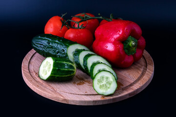 On a cutting board, cut cucumber into slices, tomatoes and red pepper.