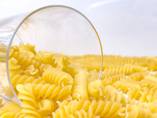 Raw dry Italian pasta in shape of spiral in glass at kitchen. Food background. Uncooked macaroni.