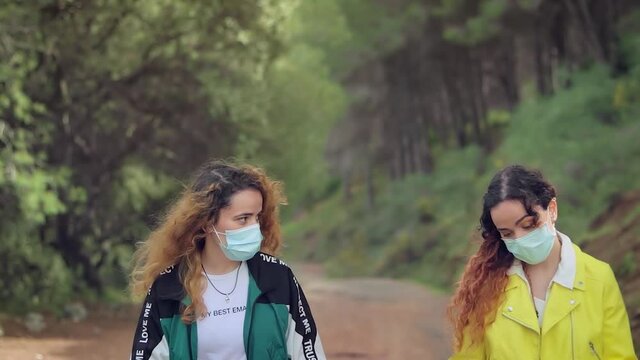 Dos hermanas gemelas riendo y charlando con complicidad en un camino del bosque