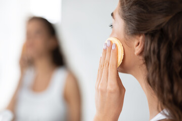 Woman Applying Face Powder With Sponge Looking In Mirror Indoors