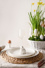 Spring stilish Easter table setting with organic eggs, bunny and blooming flowers.