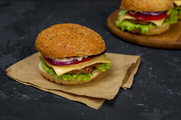 large burger with cutlet, tomato, mayonnaise, lettuce, onion rings. fast food, american food 