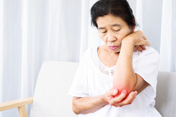 old Asian woman suffering from tennis elbow pain hand holding her ache arm