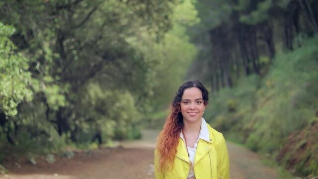 mujer sonriendo en un camino en el bosque verde cubierto por &aacute;rboles