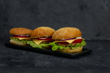 large burger with cutlet, tomato, mayonnaise, lettuce, onion rings. fast food, american food 