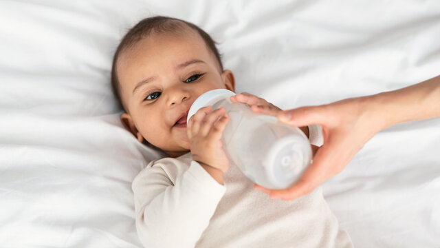Cute little African American child drinking from baby bottle