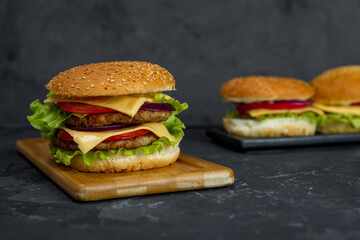 large burger with cutlet, tomato, mayonnaise, lettuce, onion rings. fast food, american food 