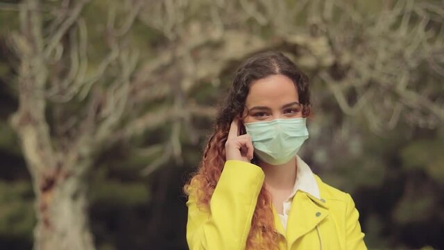 mujer posando con mascarilla delante de las ramas de un &aacute;rbol en un bosque