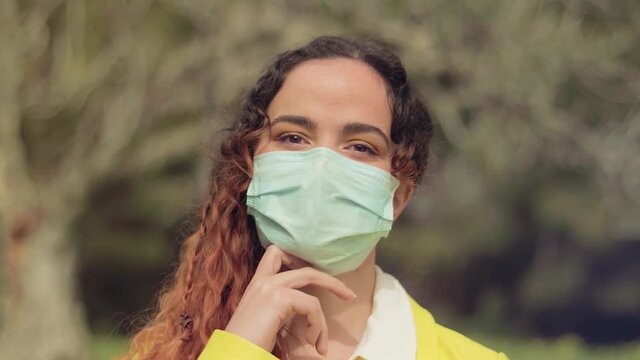 Primer plano de los ojos de una Mujer Joven con mascarilla quir&uacute;rgica en el bosque 