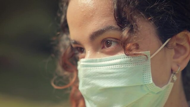 Primer plano de los ojos de una Mujer Joven con mascarilla quir&uacute;rgica en el bosque 