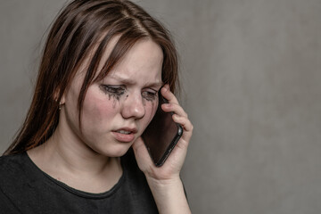 Crying teen girl talking to using a mobile phone. Empty space for text