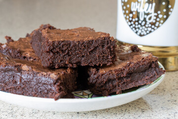 A brightly colored plate with decadent, gooey, fudge brownies with a gold and white 