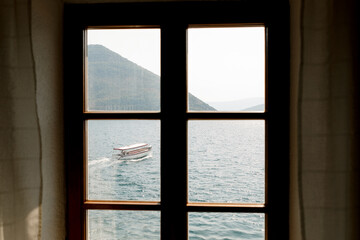 View from the window to the mountains of the town of Perast and the Bay of Kotor with a passing motorboat.