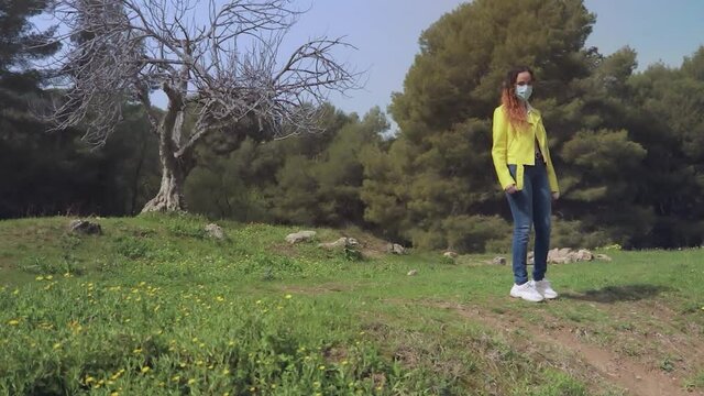 mujer Gemela se quita la mascarilla y estalla de alegría en  un prado con flores amarillas en un bosque