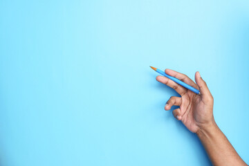 holding blue color pencil against blue background 